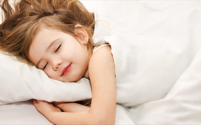 Young girl sleeping peacefully in white bedding