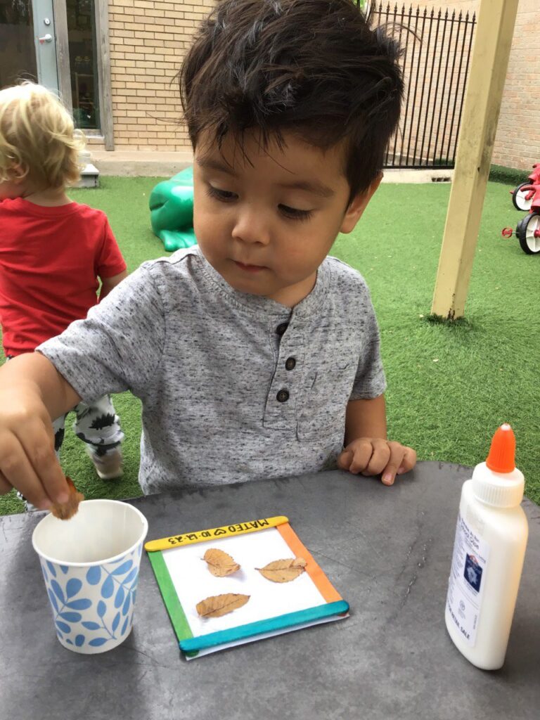 Child creating leaf craft project outdoors using glue and leaves