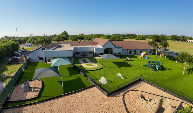 Modern playground with green lawns and play structures under the blue sky