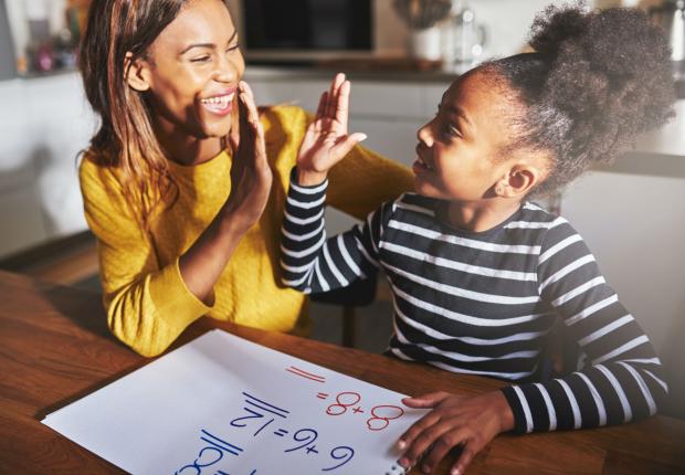 Mother and daughter solving math problems together at a table