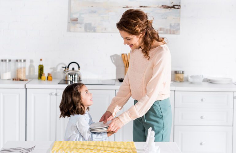 Mother and daughter smiling while setting the kitchen table together