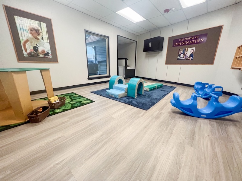 Preschool playroom with toys and activity mats on wooden floor for imaginative play