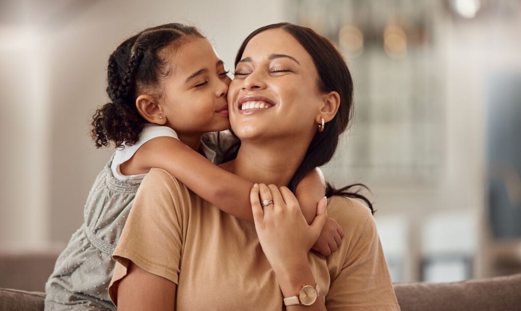 Child hugging and kissing smiling woman in cozy home setting