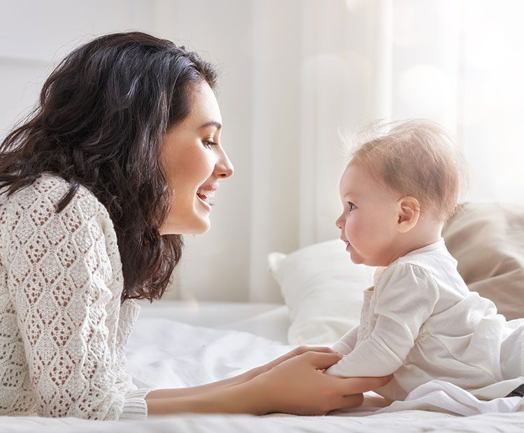 Mother and baby smiling at each other in a bright room