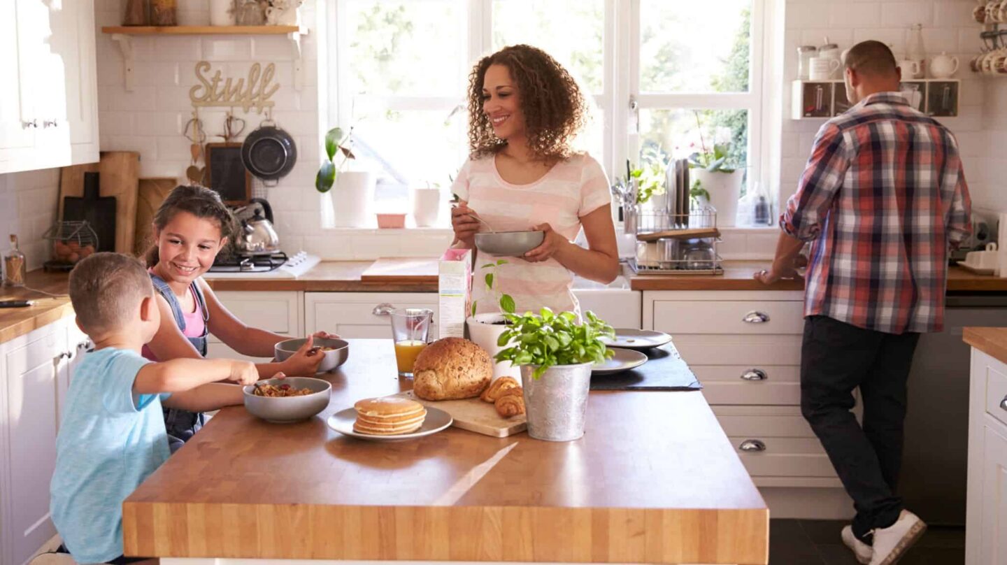 Family enjoying breakfast together in a bright kitchen with fresh bread and orange juice