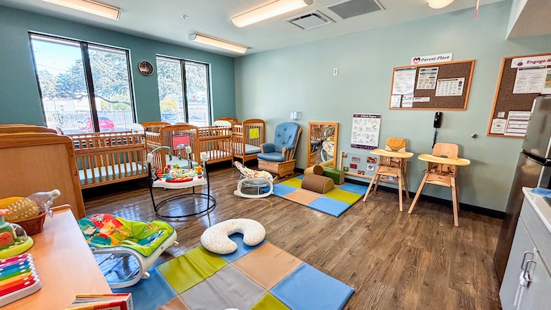 Colorful daycare room with cribs, toys, and play mats ideal for infants and toddlers activities.