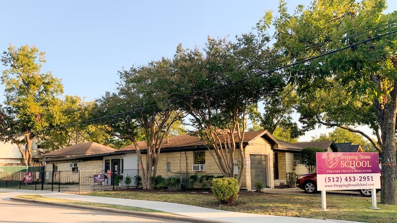 Exterior view of Stepping Stone School building with trees and sign in front of entrance