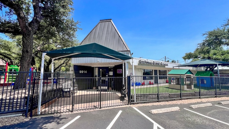 Front view of a preschool with playground and parking lot on a sunny day