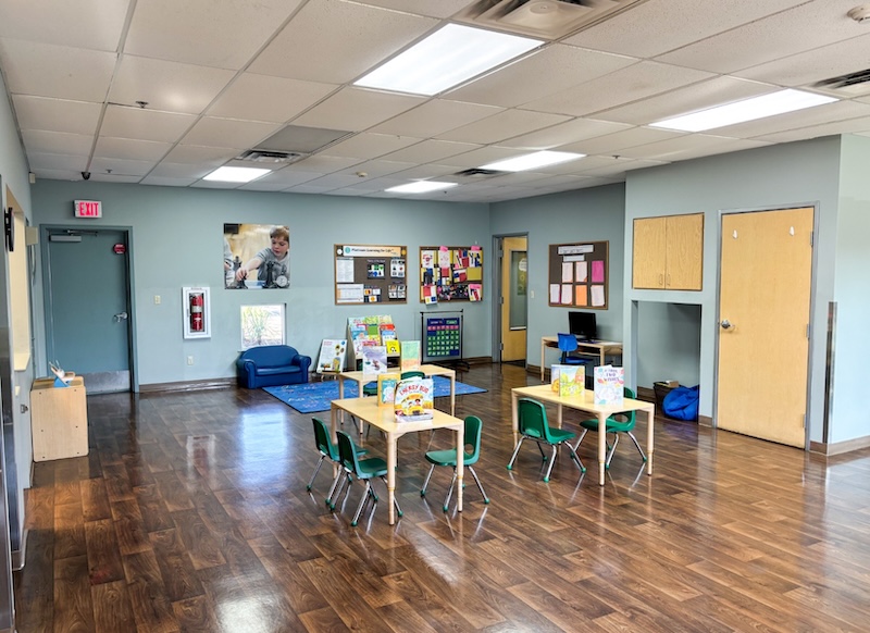 Bright and spacious preschool classroom with tables chairs and educational materials