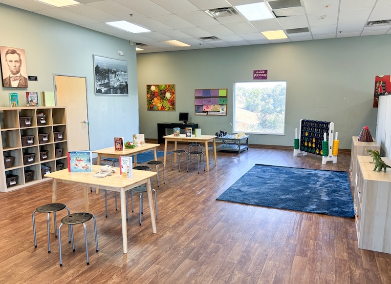 Bright classroom with tables, chairs, and colorful decorations for creative learning activities on wooden floors.