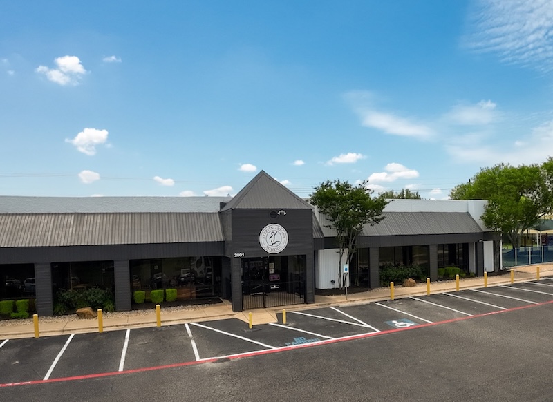 Modern commercial building with large windows under a blue sky in a suburban area