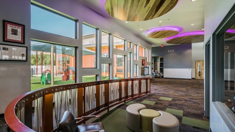 Modern indoor space with large windows and colorful decor overlooking a playground outside