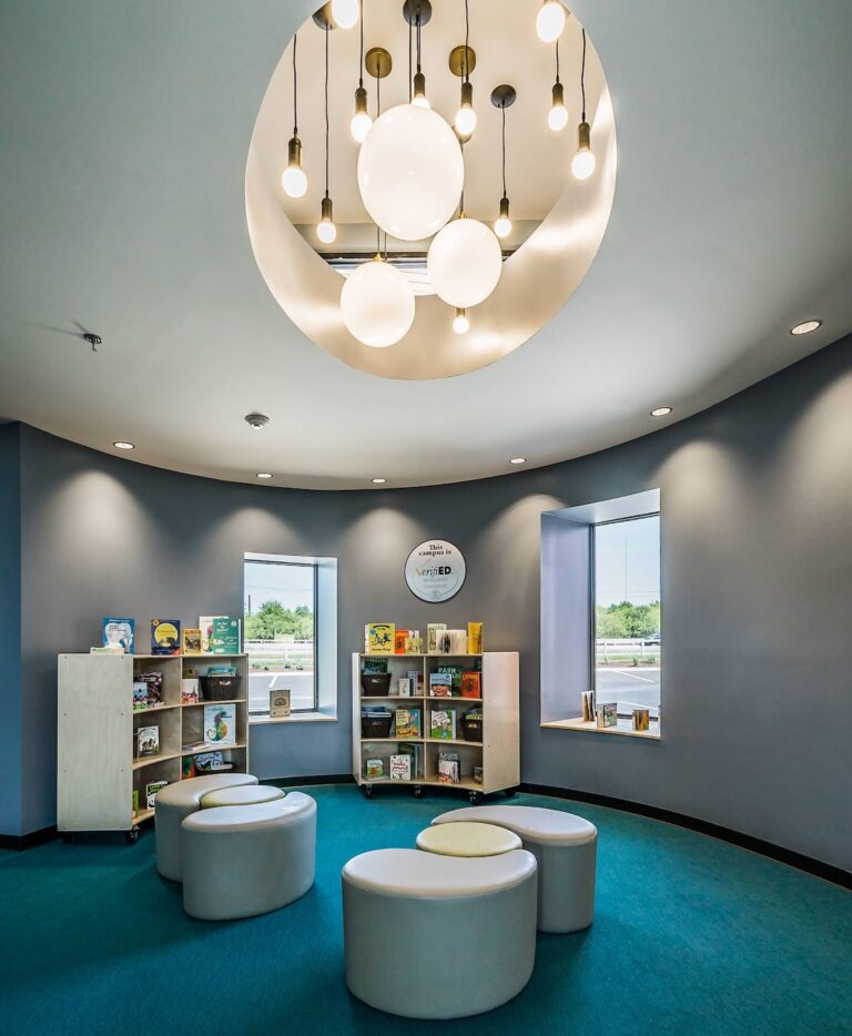 Modern library reading nook with bookshelves and circular seating under a contemporary chandelier.