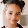 Young girl smiling indoors with hair in buns