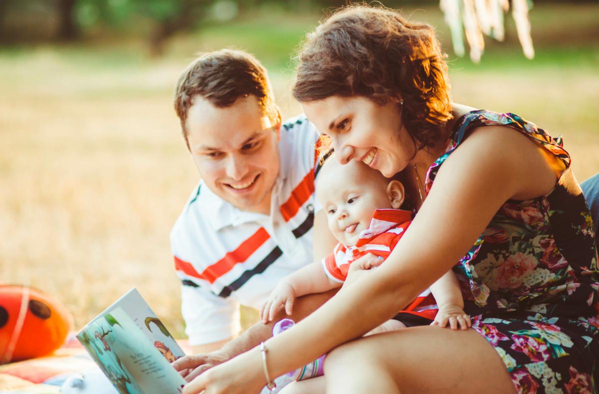 Family reading a book together on a sunny day outdoors