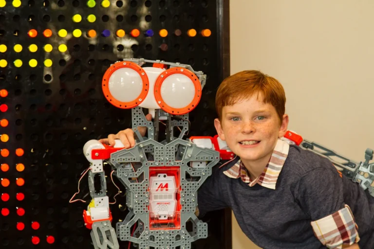 Boy smiling with a robot at a science exhibit