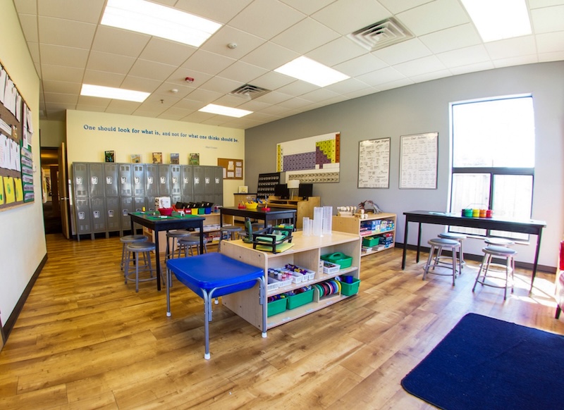 Bright classroom with organized tables shelves and lockers on wooden flooring
