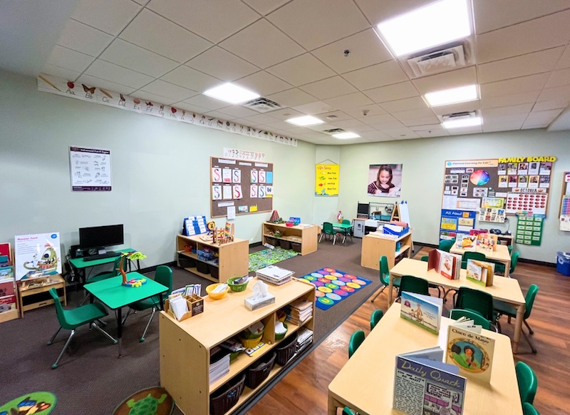 Bright and colorful kindergarten classroom with tables and educational materials displayed neatly.