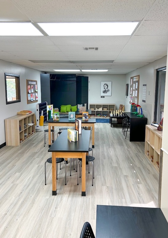 Bright classroom with tables chairs shelves books and educational decor