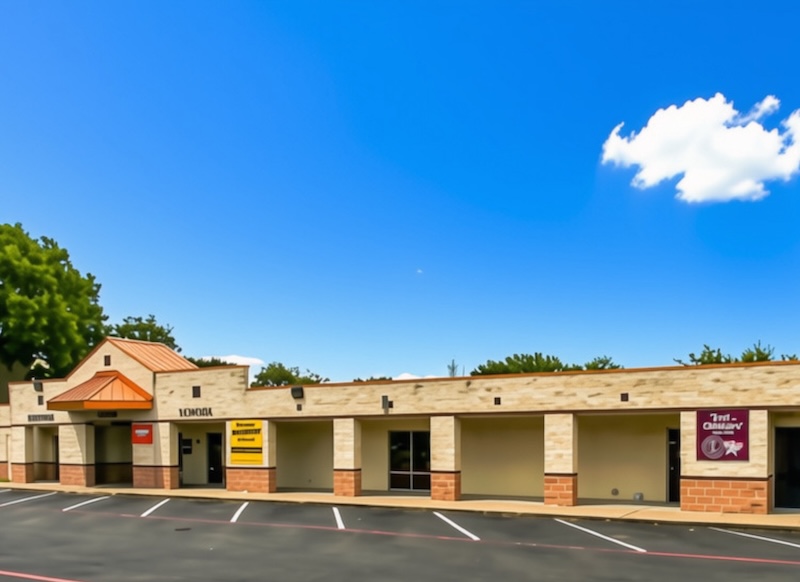 A single-story commercial building with a parking lot and clear blue sky.