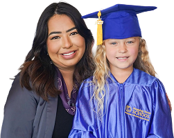 Smiling woman with a child in a blue graduation cap and gown celebrating a preschool milestone.
