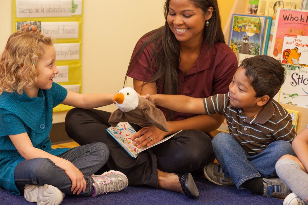 Teacher and children engaging with a puppet during storytime in a classroom setting