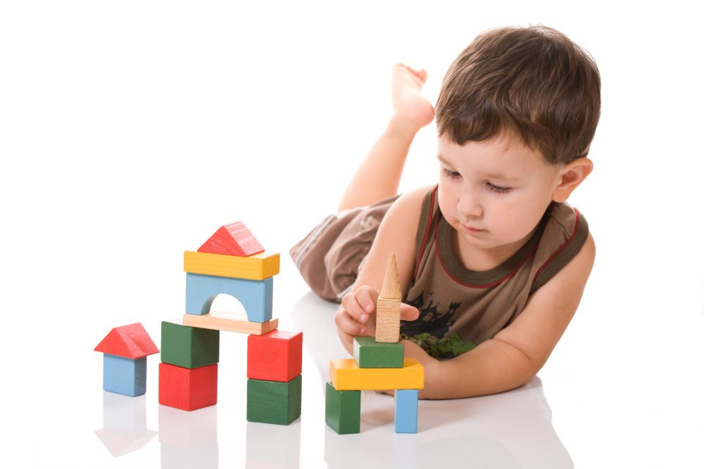 Child playing with colorful wooden blocks on white background