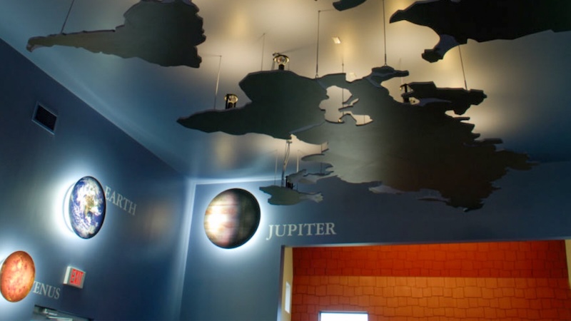 Ceiling of a planetarium showing planets Earth, Venus, and Jupiter with cloud-like sculptures above