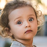 Curly-haired toddler with a curious expression outdoors
