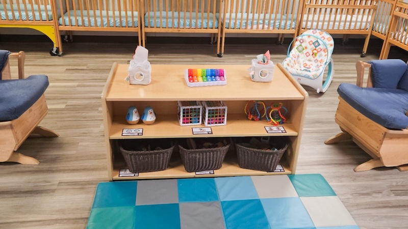 Infant daycare room with cribs toys and colorful play mat