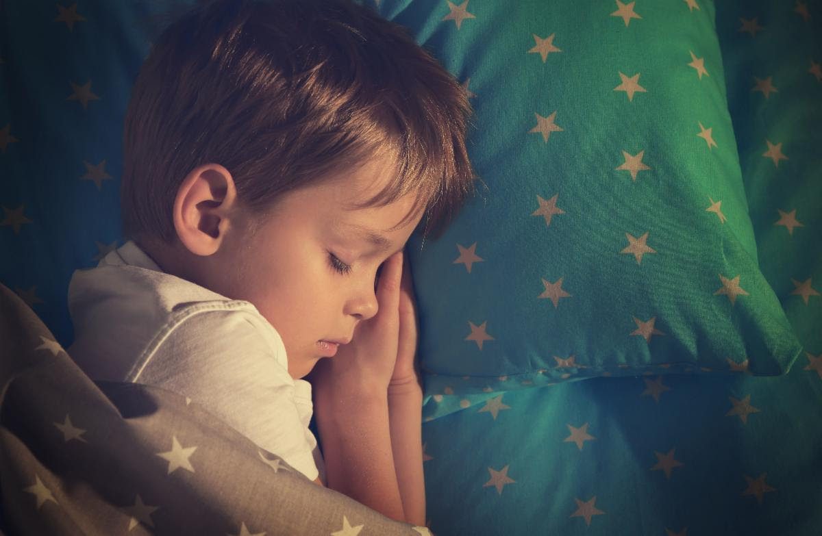 Child sleeping peacefully on star-patterned bedding.