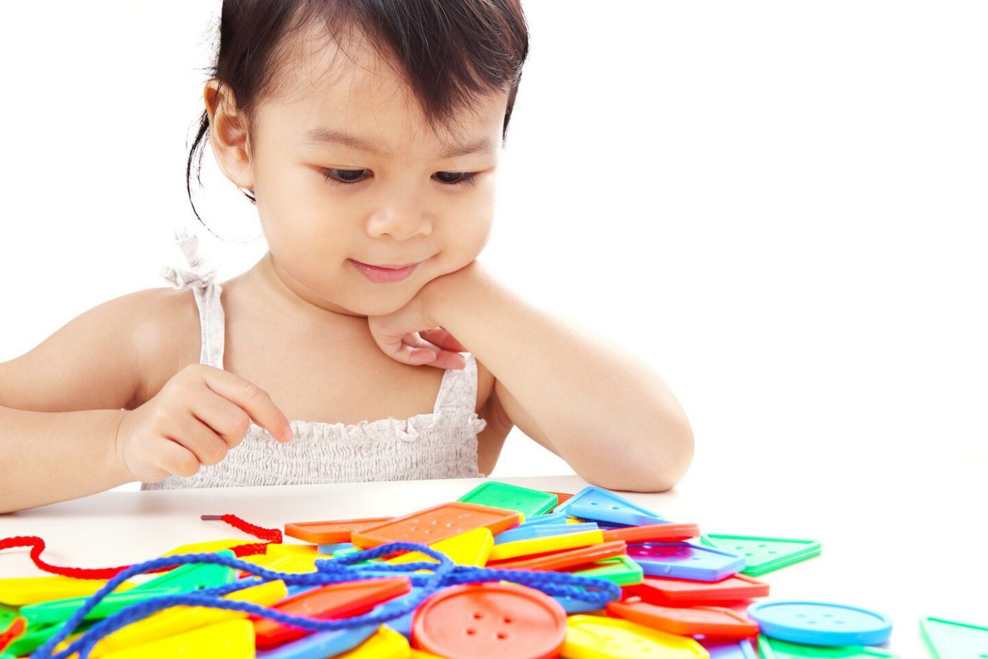 Toddler playing with colorful educational toys at a table.