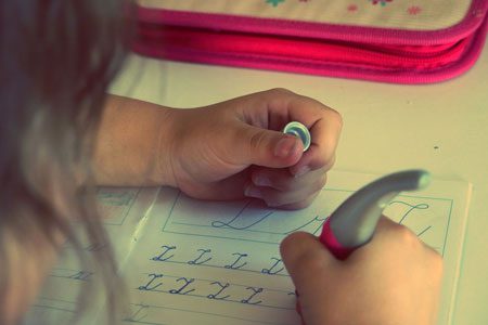 Child practicing handwriting with a pen on lined paper